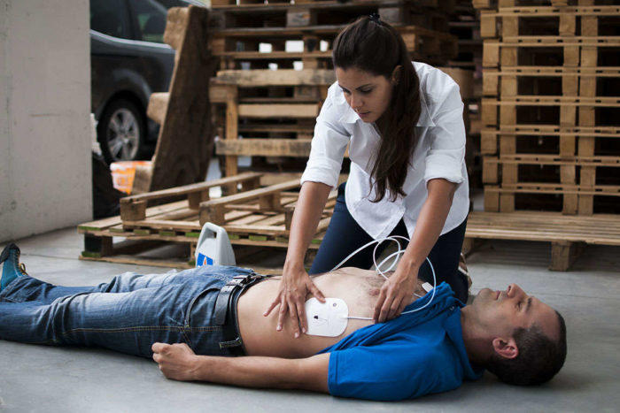 Woman applying defibrillator pads to man on floor