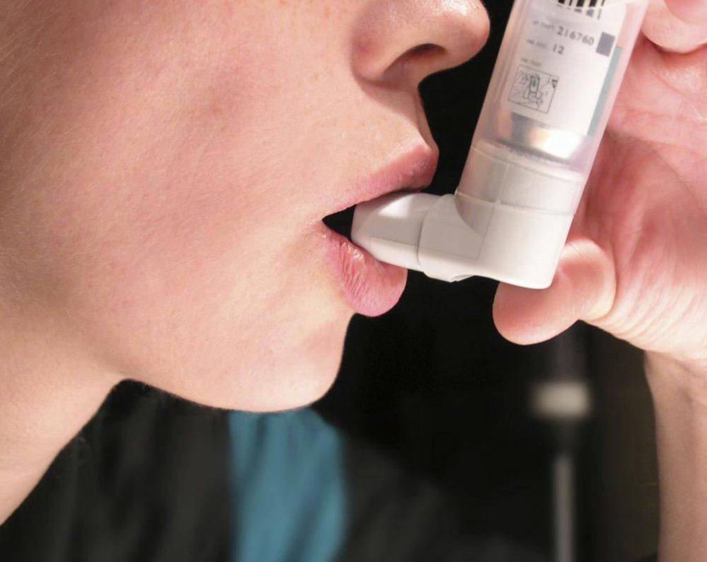 Person using asthma inhaler puffer