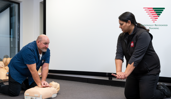 First aid trainer showing a man how to do CPR compressions